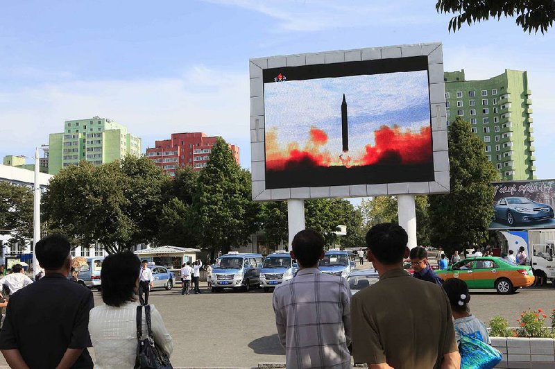 North Koreans watch the launch of a Hwasong-12 ballistic rocket as it’s shown on a television screen Saturday at a train station in Pyongyang. 