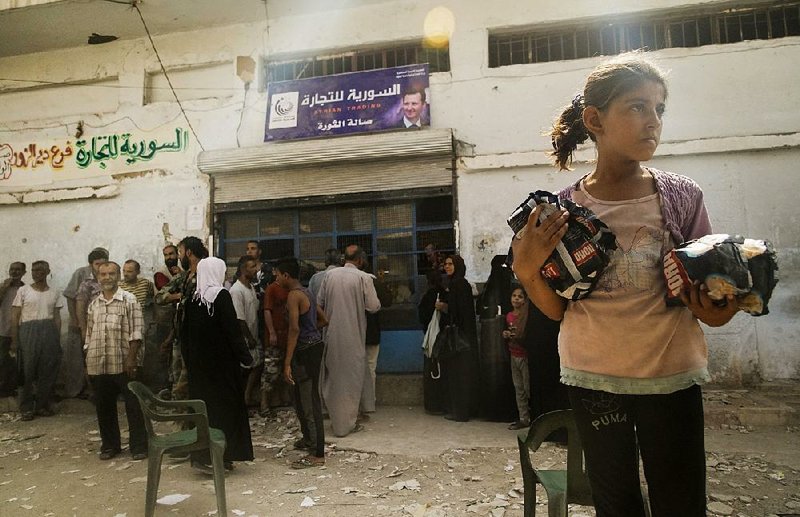 People line up Friday outside a shop in Deir el-Zour, Syria, that recently opened after Syrian forces broke an Islamic State siege.