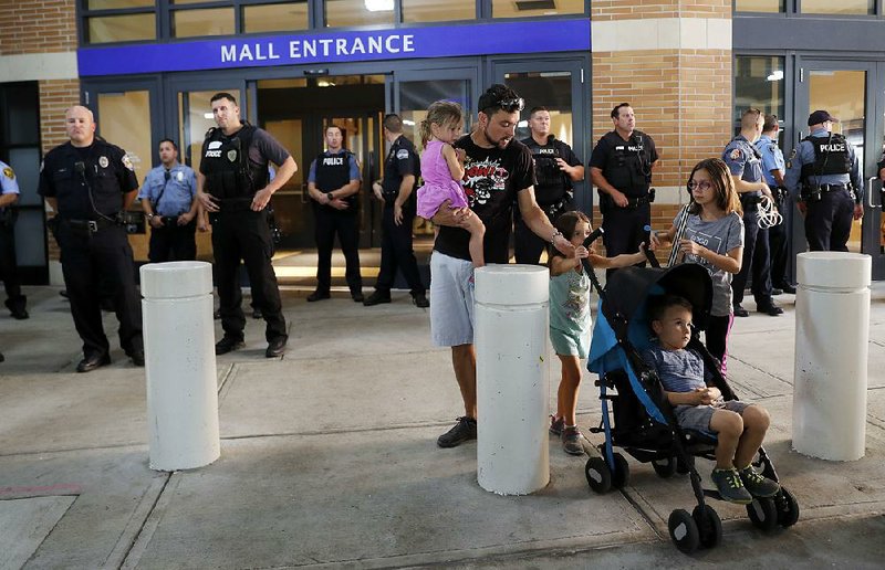 A family leaves the West County Center in Des Peres, Mo., on Saturday as police guard the entrance after hundreds of people marched inside the mall in protest against the acquittal of former St. Louis police officer Jason Stockley.  