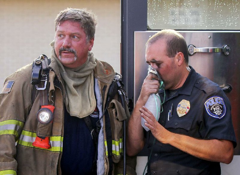 North Little Rock police officer Ryan Osborne (right) is treated for smoke inhalation after trying to save a woman trapped in her burning apartment Saturday morning at Eastgate Terrace. The woman did not survive the fire. 