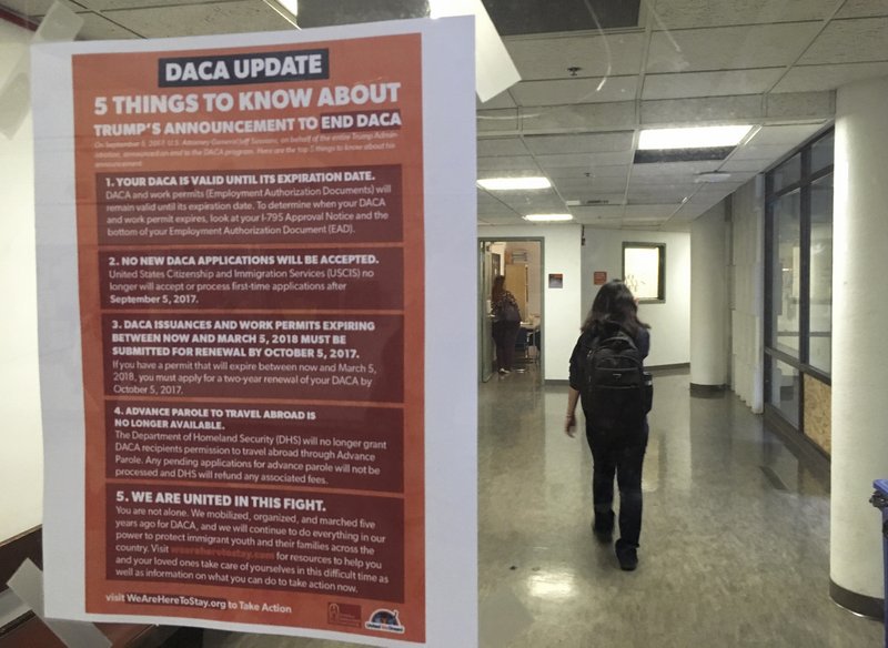 In this photo taken Sept. 7, 2017, a student walks past a tip sheet for Deferred Action for Childhood Arrivals recipients who fear deportation that is taped to a window on the University of California, Berkeley campus in Berkeley, Calif. Colleges and universities nationwide are stepping up efforts to help the students who are often called "Dreamers" after the Trump administration announced plans last week to end that federal program protecting immigrants brought to the U.S. illegally as children. (AP Photo/Jocelyn Gecker)