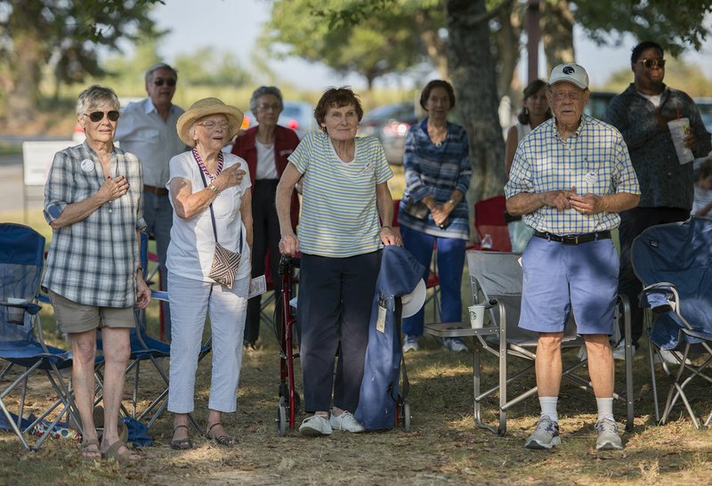 NWA Democrat-Gazette/CHARLIE KAIJO Attendees stand for the pledge of allegiance Saturday during a fundraising picnic at the city park in Little Flock. The picnic is a fundraiser for the Democratic Party of Benton County, an event with a history of at least 50 years.