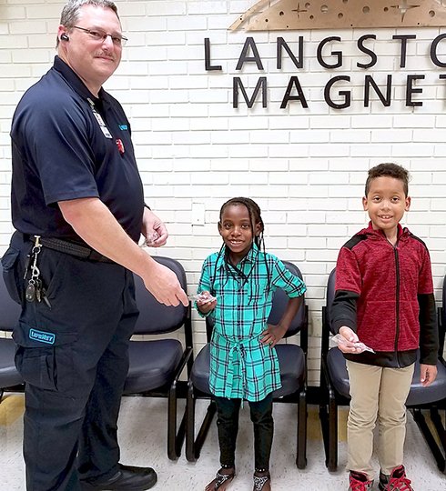 Submitted photo James Stine, left, with LifeNet, recently delivered Hannah's Lights to second-grade students Jerrell Johnson, right, and Ka'Mya Babb. Hannah's Lights are small plastic flashing lights designed to clip onto a child's backpack or clothing to help make them more visible to drivers.