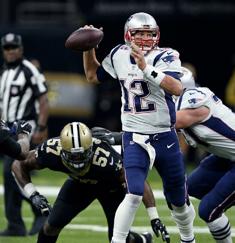 New England Patriots quarterback Tom Brady (12) passes under pressure from New Orleans Saints defensive end Alex Okafor (57) in the first half of Sunday’s game in New Orleans.