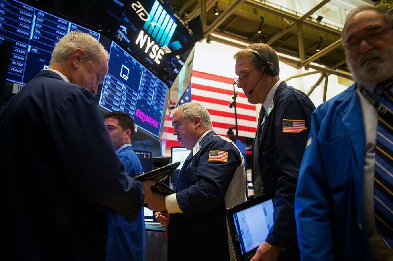 Traders work Monday at the post where Equifax Inc. shares are traded on the floor of the New York Stock Exchange.