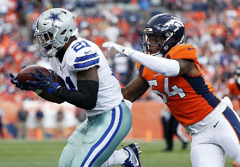 Cowboys running back Ezekiel Elliott makes a catch as Broncos inside linebacker Brandon Marshall defends during the first half Sunday in Denver. Hall of Fame running back LaDainian Tomlinson said Monday that Elliott quit against the Broncos.