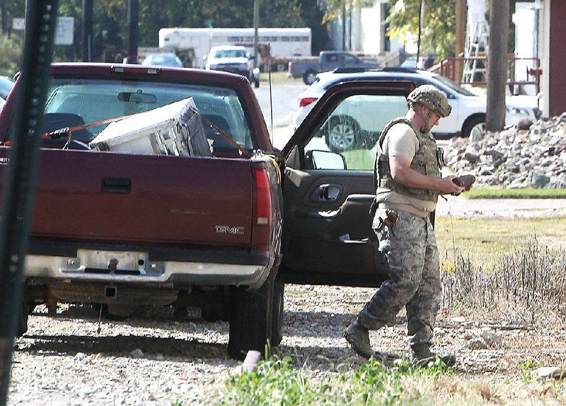 A member of a Little Rock Air Force Base  team  removes an explosive device from the front seat of a pickup Monday in the 200 block of Valley Street in Hot Springs. 