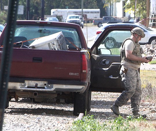 HANDLE WITH CARE: A member of the 19th Civil Engineer Squadron Explosive Ordnance Disposal team from the Little Rock Air Force Base removes a live World War I-era artillery round from the front seat of a pickup truck in the 200 block of Valley Street on Monday.