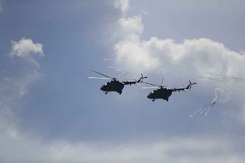 Two Belarusian military helicopters fly Tuesday during military exercises near the Volka village southwest of Minsk, Belarus. 