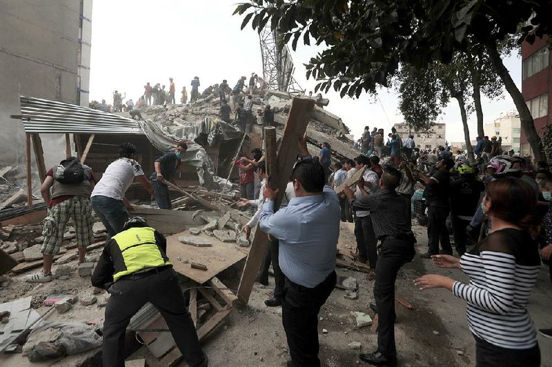 Volunteers search a collapsed building Tuesday in the Roma neighborhood of Mexico City after a strong earthquake caused dozens of buildings to fall in densely populated areas.  
