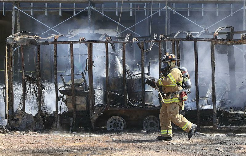 Arkansas Democrat-Gazette/STATON BREIDENTHAL --9/19/17-- A Little Rock firefighter walks past a smoldering trailer Tuesday afternoon after firefighters were called to the construction site for the new midtown clinic for Arkansas Specialty Orthopaedic and OrthoArkansas at Fair Park Blvd and i-630 to put out the fire. 
