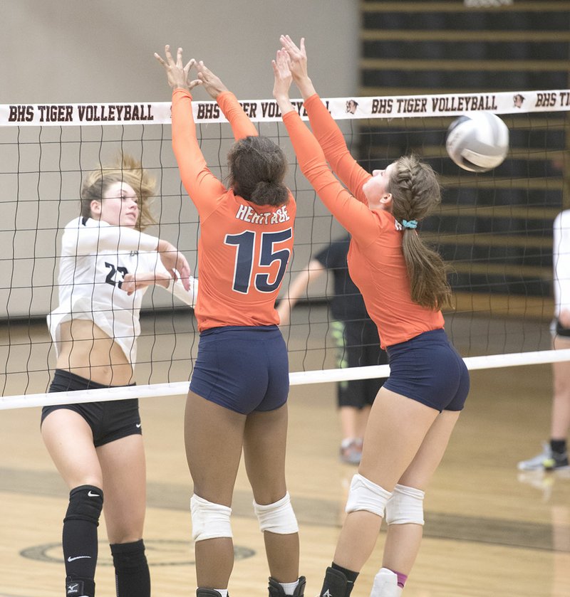 NWA Democrat-Gazette/J.T. WAMPLER Bentonville High’s Grayce Joyce (23) spikes the ball past Rogers Heritage’s Tayonna Wilson (15) and Kyndall Strickland for a kill Tuesday in Bentonville.