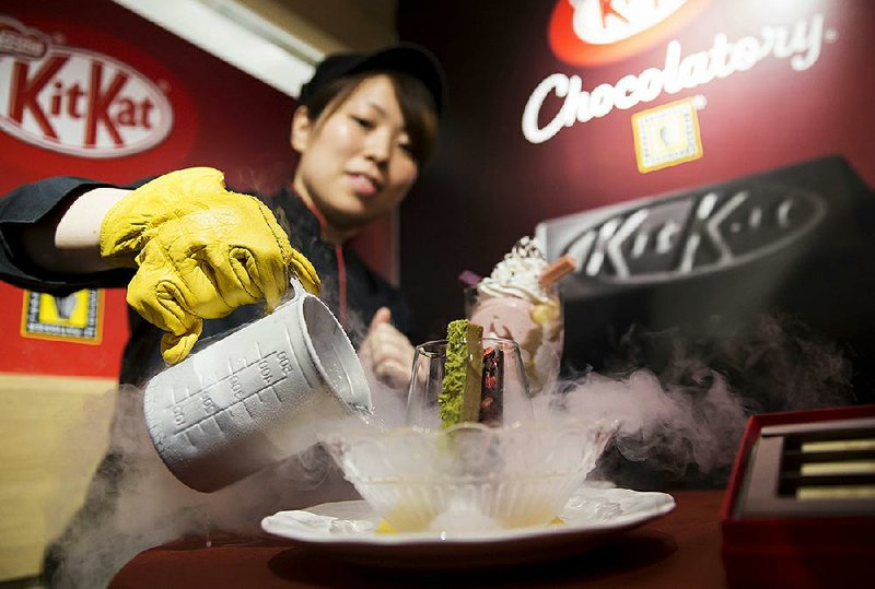 An employee pours liquid nitrogen into a bowl while serving a frozen KitKat dessert during a media preview of the KitKat Chocolatory Ginza store, operated by Nestle SA, in Tokyo, Japan. The Swiss firm is reportedly paying $500 million for a majority stake Oakland, Calif.’s Blue Bottle Coffee. 