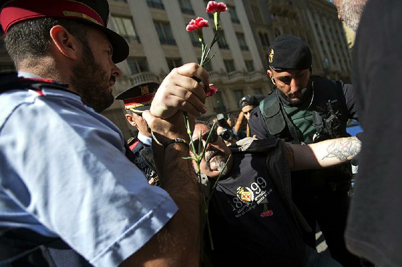 Spanish police in Barcelona arrest a protester who was attempting to block a police vehicle transporting Catalonia government official Xavier Puig, who was arrested Wednesday as part of a crackdown by national authorities on Catalonia’s plan to hold a secession referendum. Puig was one of at least 12 officials arrested Wednesday. 