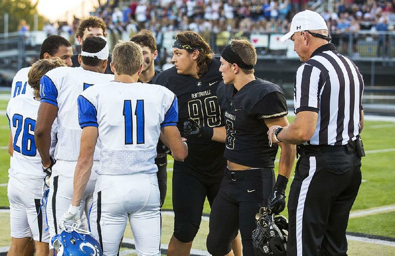 Team captains for Bentonville and Conway meet at midfield before the Wampus Cats’ 35-16 victory over the Tigers last week in Bentonville. Conway hosts Fort Smith Southside today in a 7A-Central game, while Bentonville hosts Fayetteville in a 7A-West matchup. 