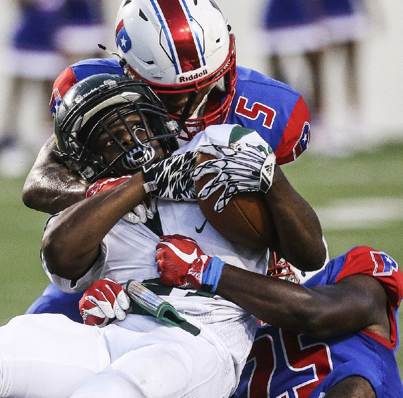 Little Rock Parkview’s Zach Smith (5) and Trevon Hadley tackle Mills running back Corbin Humphrey (middle) during the Patriots’ 67-26 victory over the Comets on Thursday at War Memorial Stadium in Little Rock.