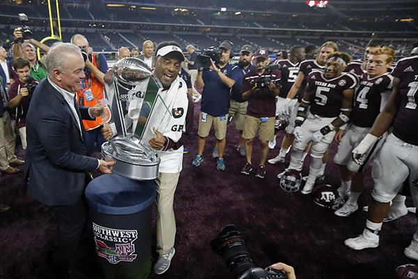 Dallas Cowboys team president Stephen Jones, left, presents Texas A&M head coach Kevin Sumlin with the Southwest Classic trophy after their win against Arkansas in an NCAA college football game, Saturday, Sept. 24, 2016, in Arlington, Texas. (AP Photo/Tony Gutierrez)

