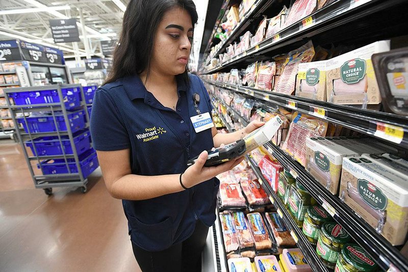 Stephany Ponce of Springdale, a personal shopper at the Wal-Mart in Rogers’ selects grocery items in May. Wal-Mart’s new program will allow food stamp recipients to order groceries online and pay for them at the store through the company’s pickup service. 