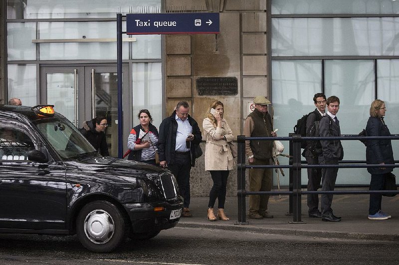 Passengers line up for taxis outside a rail station in London in this file photo. London’s transportation agency on Friday decided not to renew ride-hailing service Uber’s license to operate. 