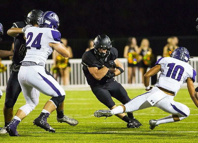 Bentonville’s Easton Miller (left) rushes past Fayetteville’s Braydon Butler during Friday night’s game at Bentonville. Miller scored on a 5-yard run in the third quarter.