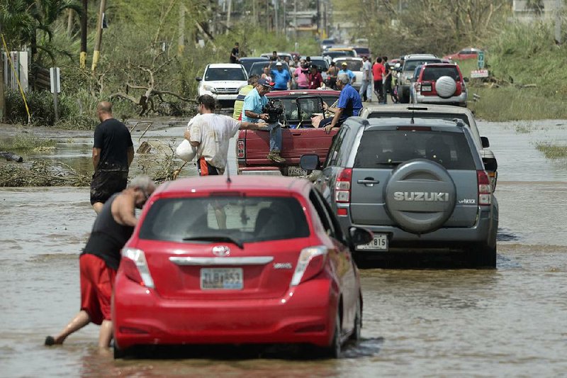 Vehicles travel a flooded road Friday after Hurricane Maria passed through Toa Baja, Puerto Rico, where thousands of people were evacuated when the gates of the Rio La Plata Dam were opened. 