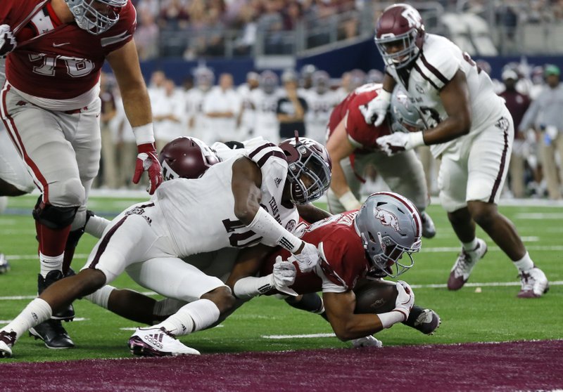 Arkansas running back Chase Hayden (2) dives into the end zone for a touchdown under the attempted stop by Texas A&M defensive back Myles Jones (10) in the first half of an NCAA college football game, Saturday, Sept. 23, 2017, in Arlington, Texas. (