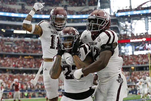 Texas A&M defensive back Larry Pryor, left, defensive back Armani Watts, center, and linebacker Otaro Alaka (42) celebrate an interception by Watts in overtime of an NCAA college football game against Arkansas, Saturday, Sept. 23, 2017, in Arlington, Texas. Texas A&M won 50-43. (AP Photo/Tony Gutierrez)

