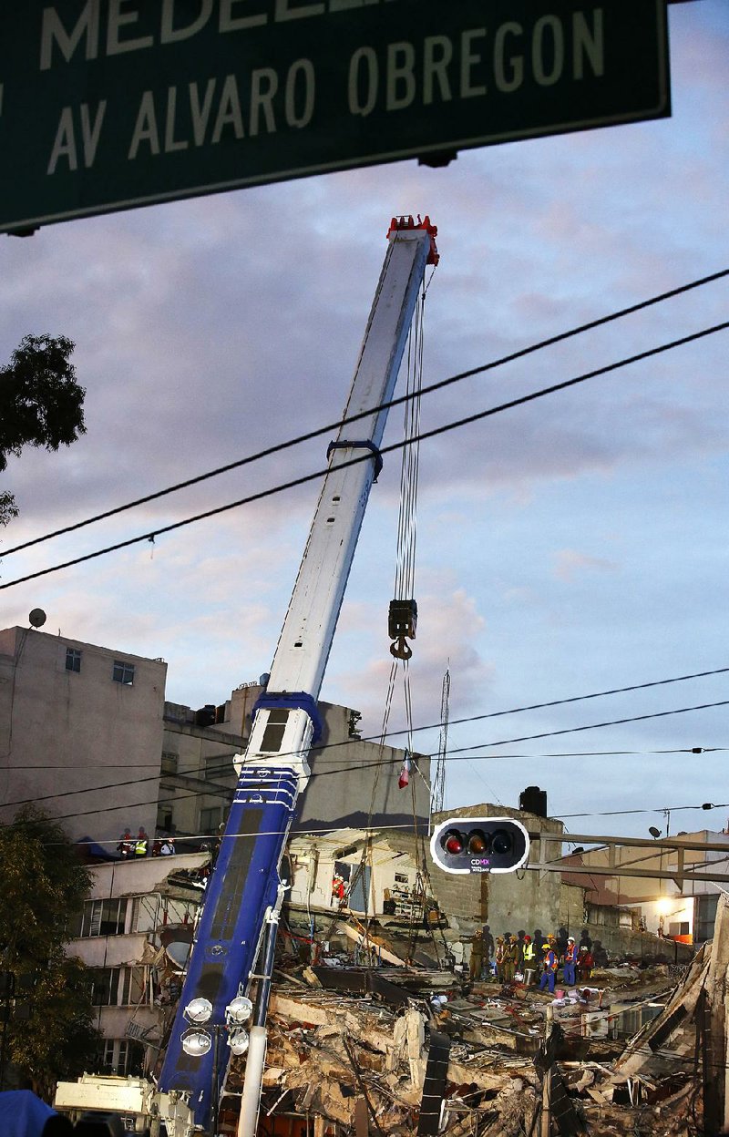 Rescuers use a crane to lift part of a collapsed building Saturday in Mexico City’s Roma Norte neighborhood as they search for survivors after a 6.1-magnitude earthquake.