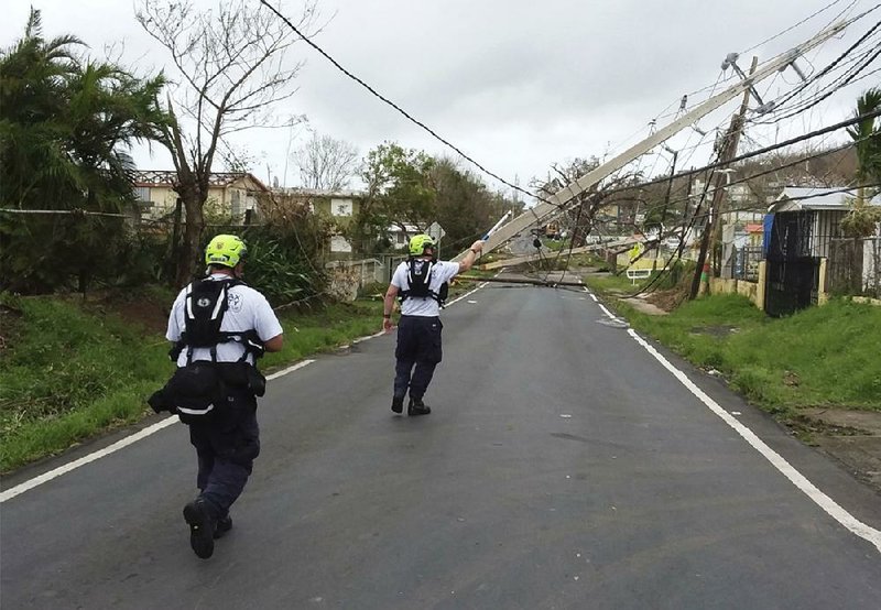 Workers in eastern Puerto Rico use a hot stick to assess power lines Friday in this photo provided by the Virginia Task Force 1 rescue group.