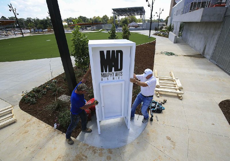 Craig Garrett (left) and Bob Whitehouse work Thursday to install the sign for the new amphitheater in the Murphy Arts District in downtown El Dorado.