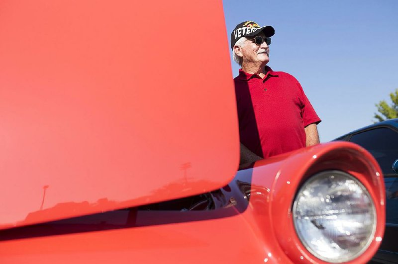 Bill Price of Elkins takes a picture next to a 1956 Ford Thunderbird on Saturday during the Bikes, Blues and BBQ car show at Arvest Ballpark in Springdale.  