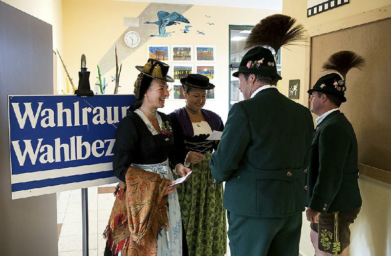 People in traditional Bavarian attire stand at a polling station before casting their votes in the German Parliament election in Unterwoessen, southern Germany, on Sunday.