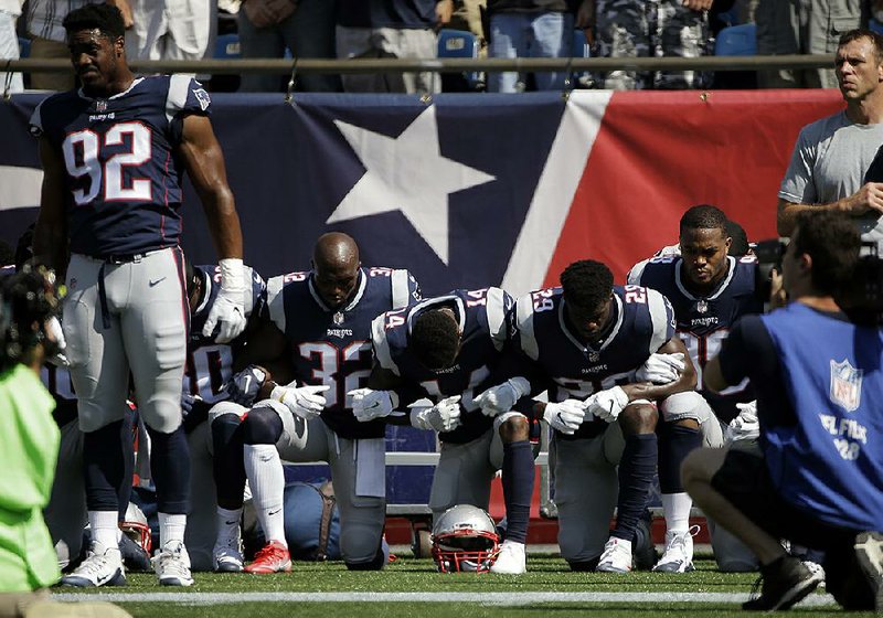 New England Patriots players kneel during the national anthem before their game Sunday with the Houston Texans in Foxborough, Mass. Other players stood and locked arms.