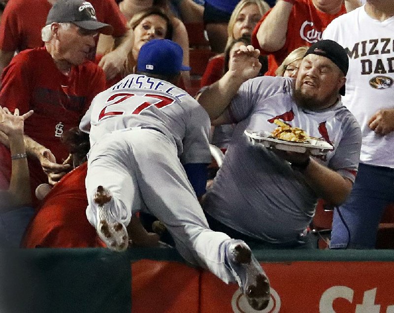 Chicago Cubs’ shortstop Addison Russell dives into the stands while chasing a foul ball during the second inning against the St. Louis Cardinals on Monday night in St. Louis. The Cubs defeated the Cardinals 10-2, moving within a victory of clinching their second consecutive division title.
