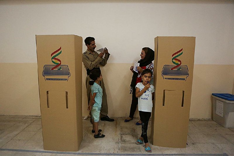 A Kurdish man in Irbil, Iraq, takes a picture as his wife shows her ballot during voting in Monday’s independence referendum.