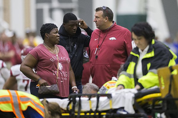 Arkansas coach Bret Bielema, right, talks with Brian Williams, center, and Kim Williams while emergency personnel tend to Rawleigh Williams during a practice Saturday, April 29, 2017, in Fayetteville. 