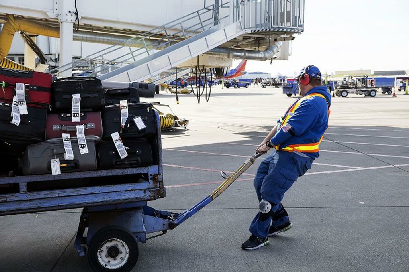 A Southwest Airlines ramp agent hauls luggage to load on a flight departing Dallas Love Field in this March file photo. The airline industry, in the midst of one of its most financially stable eras in decades, is better able now to handle the short-term effects of this year’s hurricane season, industry analysts say. 