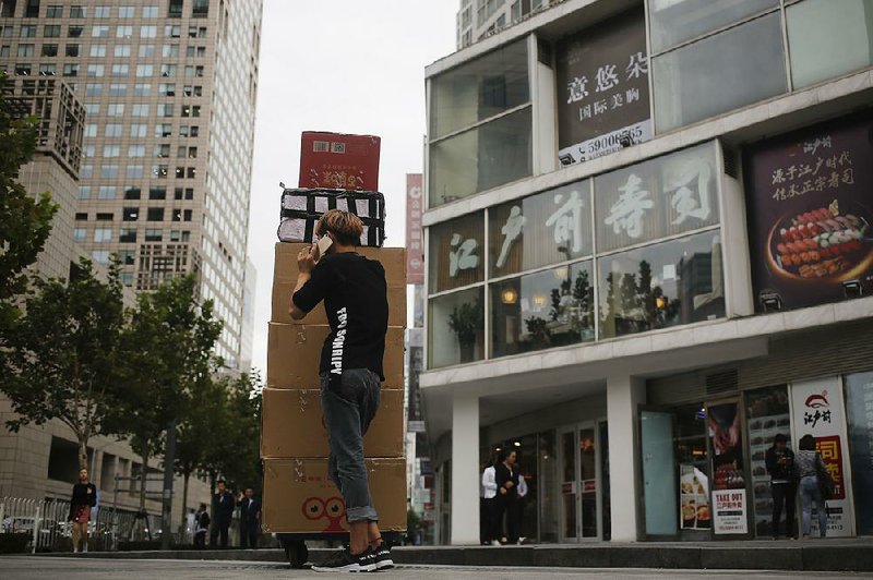 A deliveryman pushes a cart loaded with boxes of dried foods near a sushi restaurant at a commercial building in Beijing on Tuesday. China has delayed enforcing new controls on food imports set to take effect Sunday. 