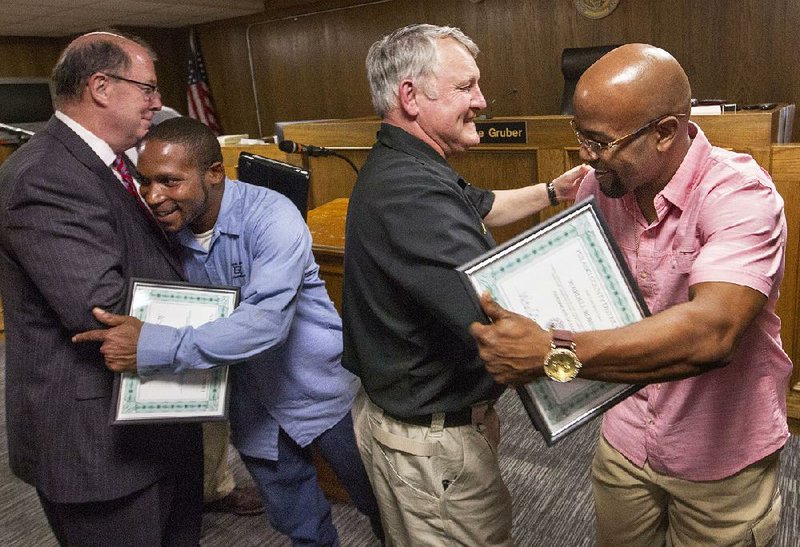 Two graduates from Pulaski County District Court’s sobriety court — Fotra Jones (second from left) and Wardell Robinson (right) — are congratulated by Pulaski County Judge Barry Hyde (left) and Pulaski County Sheriff Doc Holladay for completing a yearlong program that allows people twice convicted of DWI to enter a court-supervised rehabilitation program to avoid incarceration and fines.