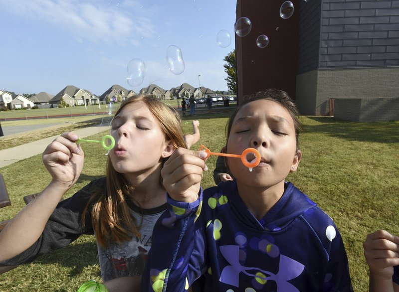 NWA Democrat-Gazette/FLIP PUTTHOFF Arden Cearley (left) and Carson Stoyanov, students at Central Park Elementary School in Bentonville, test liquids Tuesday for blowing bubbles as part of a class project.