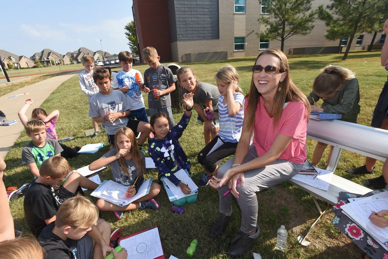 NWA Democrat-Gazette/FLIP PUTTHOFF Amy Holland, teacher at Central Park Elementary School in Bentonville, helps students Tuesday write a report on about their bubble-blowing research.