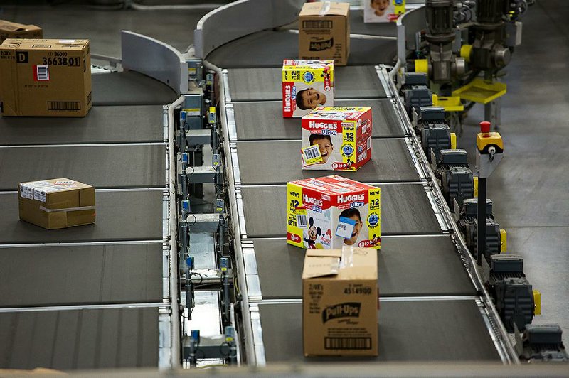 Packages of Huggies brand diapers move along a conveyor belt at a Wal-Mart warehouse for online orders in Bethlehem, Pa., earlier this year. Wal-Mart said Wednesday that it plans to expand its Parent’s Choice brand of baby products. 