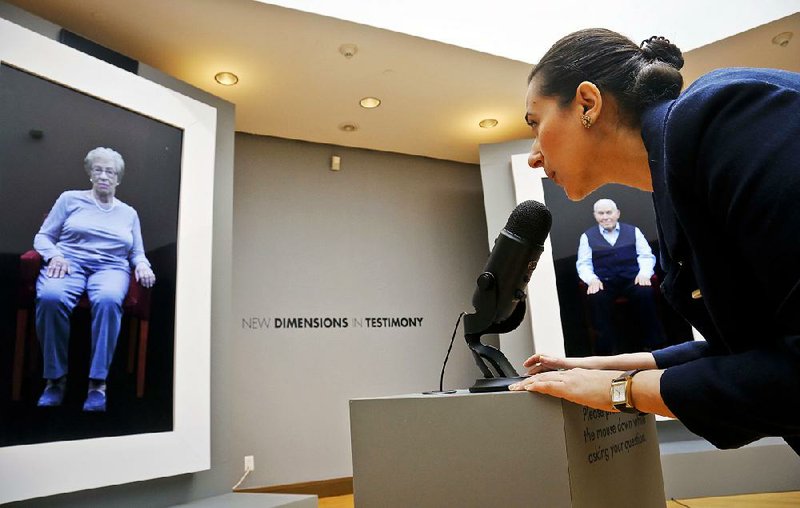 Josephine Mairzadeh (right) uses a microphone to pose a question to a virtual presentation of Holocaust survivor Eva Schloss in the interactive installation “New Dimensions in Testimony” at New York’s Museum of Jewish Heritage. 