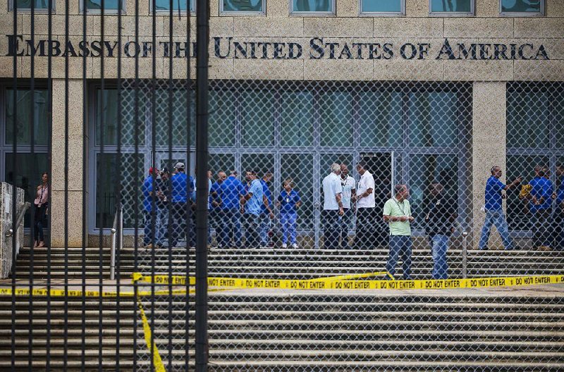 Workers at the U.S. Embassy in Havana stand behind a gate and security barrier Friday.
