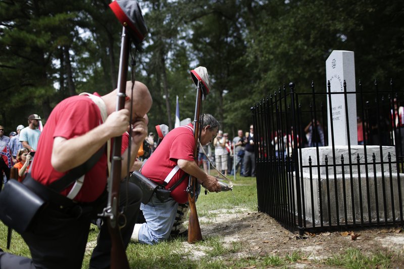 FILE- In this Aug. 27, 2017 file photo members of the Sons of Confederate Veterans kneel in front of a new monument called the "Unknown Alabama Confederate Soldiers" in the Confederate Veterans Memorial Park in Brantley, Ala. As Confederate statues across the nation get removed, covered up or vandalized, some brand new ones are being built as well. (AP Photo/Brynn Anderson, File)