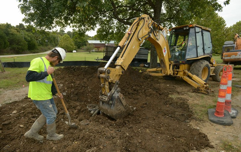 NWA Democrat-Gazette/ANDY SHUPE
Chase Goins (left) uses a shovel Thursday, Sept. 28, 2017, while helping his father, Terry Goins of Goins Enterprises in Joplin, Mo., as he uses a backhoe to bury a newly installed water main tap at Smokehouse Trail and Martin Luther King Jr. Boulevard in Fayetteville. Goins Enterprises is working to install a new water main at the site to serve Farmington and is also replacing a water line on Huntsville Road and at Garden Park Apartments in Fayetteville.