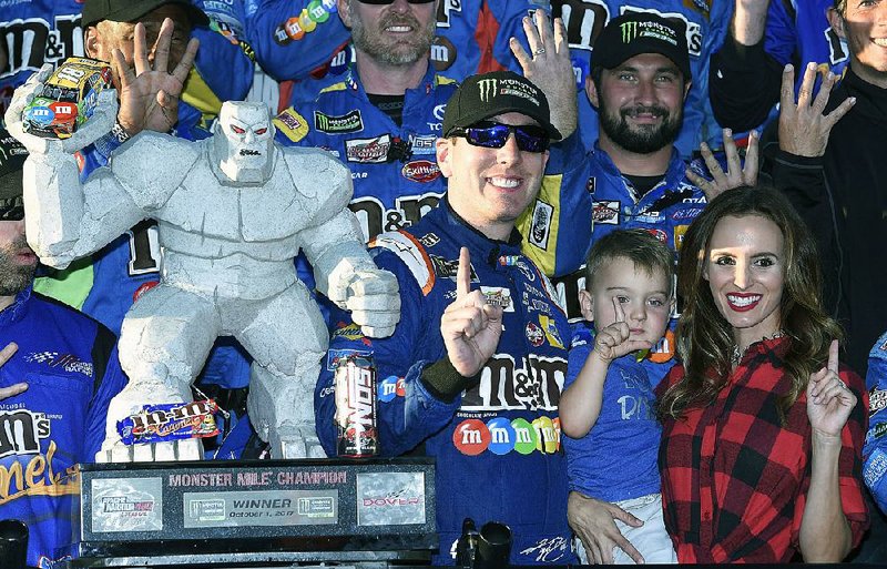 Kyle Busch, third from right, poses with the trophy with his son Brexton, second from right, and wife Samantha, right, after he won the NASCAR Cup Series auto race, Sunday, Oct. 1, 2017, at Dover International Speedway in Dover, Del. 
