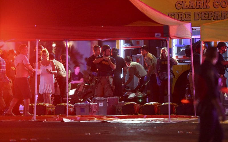 Medics treat the wounded as Las Vegas police respond during an active shooter situation on the Las Vegas Stirp in Las Vegas Sunday, Oct. 1, 2017. Multiple victims were being transported to hospitals after a shooting late Sunday at a music festival on the Las Vegas Strip. (Chase Stevens/Las Vegas Review-Journal via AP)
