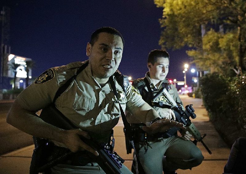 Police officers advise people to take cover late Sunday near the scene of a mass shooting outside the Mandalay Bay Resort and Casino on the Las Vegas Strip.