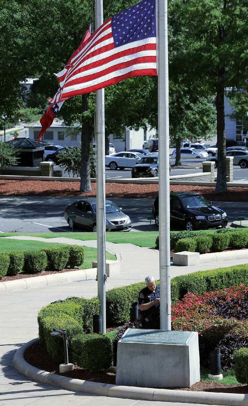 Darrell Hedden, Arkansas Capitol chief of police, adjusts the flags in front of the Capitol building Monday after a White House directive to lower flags in mourning for Las Vegas shooting victims.